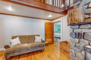 a living room with a couch and a stone fireplace at Lakefront home with outdoor firepit & private dock - near downtown in Greenville
