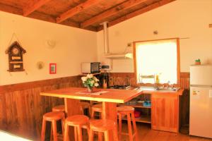 cocina con mesa de madera y taburetes en Cabañas Rapallo, en Licán Ray