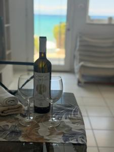 a bottle of wine and two wine glasses on a table at Seafront Maisonette in Fourka in Fourka