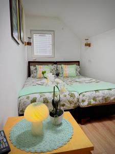 a bedroom with two beds and a table with a lamp at Apartmani Hena in Sjenica