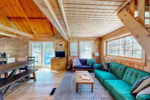 a living room with a green couch and a table at Cozy woodsy Cabin w/ a Deck, Firepit, Gas Grill, Free WiFi, & Full Kitchen in Greenville