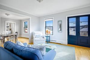 a living room with a blue couch and a table at Waterfront Duplex, walkable, harbor views, AC, dog friendly in Camden