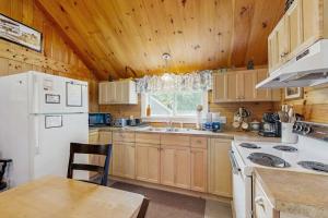 a kitchen with wooden cabinets and a white refrigerator at Lakefront, cabin-inspired home with firepit, grill, & screened porch, Wifi in Greenville