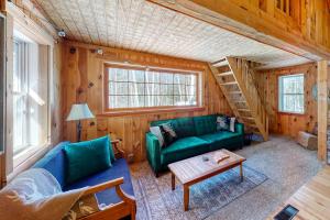 a living room with a green couch and a table at Cozy woodsy Cabin w/ a Deck, Firepit, Gas Grill, Free WiFi, & Full Kitchen in Greenville