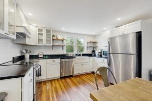 a kitchen with white cabinets and a stainless steel refrigerator at Coastal charmer with screened-in porch, grill, & AC in Boothbay Harbor +16 photos