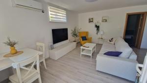a living room with a white couch and a table at Apartman Jurjević in Krk