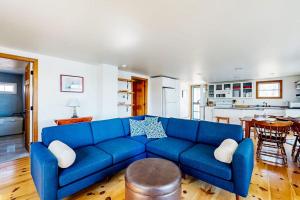 a blue couch in a living room with a kitchen at Dog-friendly river-view home with wood stove, deck, patio, dock, beach, grill in Boothbay