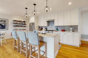 a kitchen with white cabinets and a island with bar stools at Elegant home with veranda & water view, walk to downtown Boothbay Harbor in Boothbay Harbor +13 photos