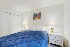 a bedroom with a blue bed and two night stands at Newly-furnished condo with loft, fast WiFi, partial AC, grills & yard access in Bar Harbor