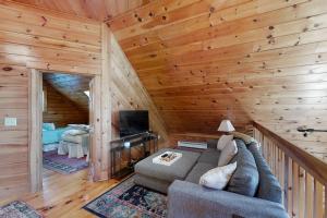 a living room with a couch and a television in a cabin at Stunning & Spacious Log Cabin in the Woods in Boothbay Harbor