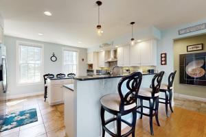 a kitchen with a bar with chairs around it at Expansive Modern Home w/ Ocean View, Gorgeous Garden & Dog-friendly in East Boothbay +18 photos