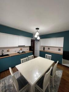 a kitchen with a white table and white chairs at Zirek House in Bishkek