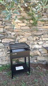a barbecue grill sitting in front of a stone wall at La Chouette in Pieve di Teco