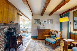 a living room with a brick fireplace and a chair at Charming Seaside Cottage with a Gas Fireplace, Spacious Patio, and Nearby Hiking in Hancock