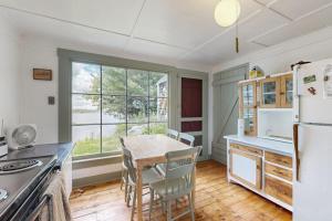a kitchen with a table and chairs and a refrigerator at Historic riverfront home with boathouse & private dock - dogs OK in Boothbay