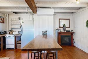 a kitchen with a wooden table and a white refrigerator at Iconic downtown retreat with firepit & fireplace- walk to Harbor Footbridge in Boothbay Harbor