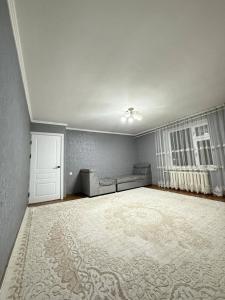 an empty living room with a couch and a window at Zirek House in Bishkek +6 photos