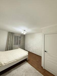 a white bedroom with a bed and a window at Zirek House in Bishkek
