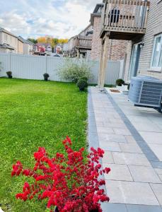 ein Garten mit roten Blumen in einem Hof in der Unterkunft New Cosy bright and Spacious Apartment in East Gwillimbury