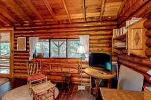 a living room with a desk and a television in a log cabin at Stunning log cabin with fireplace & nature views - near shopping & dining in Boothbay Harbor