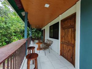 a porch with chairs and tables and a wooden door at Cabinas Toucan in Chachagua