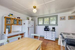 a kitchen with a table and a white refrigerator at Historic riverfront home with boathouse & private dock - dogs OK in Boothbay