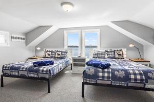 two beds in a room with two windows at Cobbossee Hideaway, lakefront property with dock for swimming, fishing, and sunrises in Winthrop
