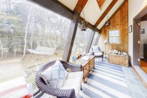 a screened in porch with wicker chairs and a large window at Appalachee Pond Waterfront Cottage | Decks, Sunroom, Dock with Kayaks & Canoe in Boothbay Harbor