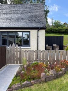 a fence in front of a house with a garden at Ben Wyvis View Annexe in Inverness