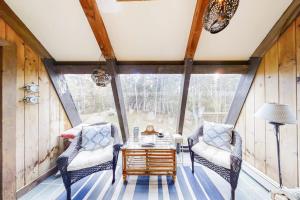 a screened in porch with two chairs and a table at Appalachee Pond Waterfront Cottage | Decks, Sunroom, Dock with Kayaks & Canoe in Boothbay Harbor
