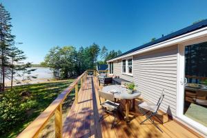 a deck with a table and chairs on a house at Newly-built waterfront home with fast WiFi, furnished deck, & washer/dryer in Waldoboro