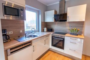 a kitchen with white cabinets and a sink and a microwave at Monique in Lenz