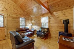 a living room with leather furniture in a log cabin at Comfortable two bedroom cabin with firepit, kitchen, hiking trail within walking in Northport