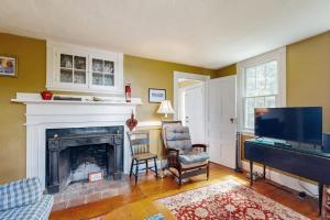 a living room with a fireplace and a flat screen tv at Historic riverfront home with boathouse & private dock - dogs OK in Boothbay