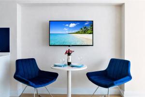 a table with two blue chairs and a tv on a wall at Royal Sea View Batumi in Batumi