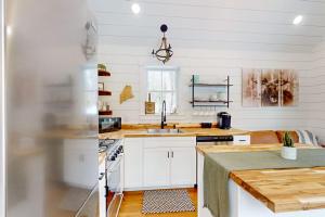 a kitchen with white cabinets and a sink at Brand-new dog-friendly home near Hancock Pond with firepit, grill, streaming, AC in Bucksport