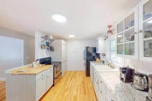 a large kitchen with white cabinets and wooden floors at Waterfront home with deck, patio, grill, firepit, Ping-Pong, & WiFi in Somesville +30 photos
