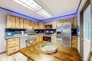 a kitchen with a wooden table and a refrigerator at Open layout Maine cottage with washer/dryer & grill - dog-friendly in Gouldsboro +9 photos