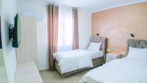 a bedroom with two beds and a tv and a window at Family Inn in Subotica