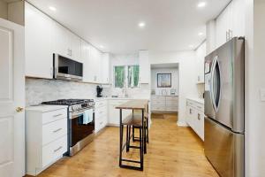 a kitchen with white cabinets and a stainless steel refrigerator at Oceanfront snowbird-friendly home on the beach with washer/dryer & fireplace in Lincolnville +16 photos