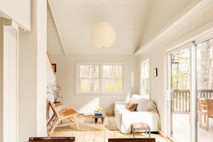 a living room with a white couch and a table at Renovated woodland home with lovely deck & firepit - minutes to Swan Lake in Swanville +19 photos