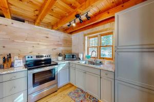 a kitchen with a stove and a sink at Cozy woodsy Cabin w/ a Deck, Firepit, Gas Grill, Free WiFi, & Full Kitchen in Greenville