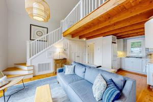 a living room with a blue couch and stairs at Periwinkle Cottage | Sunny cottage in Westport Island overlooking the river in Westport