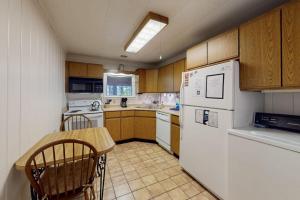 a kitchen with a white refrigerator and a table at Lakefront Home with Private Dock, Pebble Beach & Enclosed Porch - Dogs Welcome in Greenville Junction