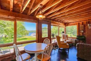 a dining room with a table and chairs and windows at Classic home overlooking the St George River with deck & great views in Saint George +9 photos