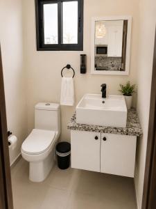 a white bathroom with a toilet and a sink at Eco Avalon Paradise Villa in Punta Cana +13 photos