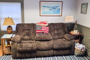 a living room with a couch with an american flag pillow on it at Open layout Maine cottage with washer/dryer & grill - dog-friendly in Gouldsboro
