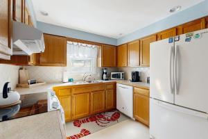 a kitchen with wooden cabinets and a white refrigerator at Charming Coastal House with Cozy Living Spaces and Outdoor Firepit in Winter Harbor +13 photos
