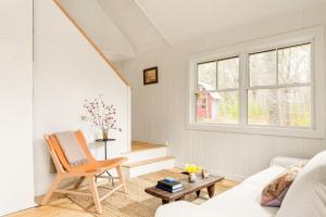 a white living room with a chair and a table at Renovated woodland home with lovely deck & firepit - minutes to Swan Lake in Swanville
