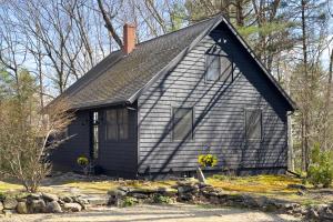 a black house with a black roof at Renovated woodland home with lovely deck & firepit - minutes to Swan Lake in Swanville